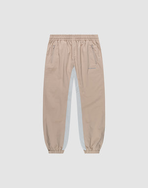 The LIVE FAST DIE YOUNG Basic Shell Pants are beige joggers with an elastic waistband, zippered side pockets, elastic cuffs, and a white vertical stripe with reflective print for style and visibility. | plain