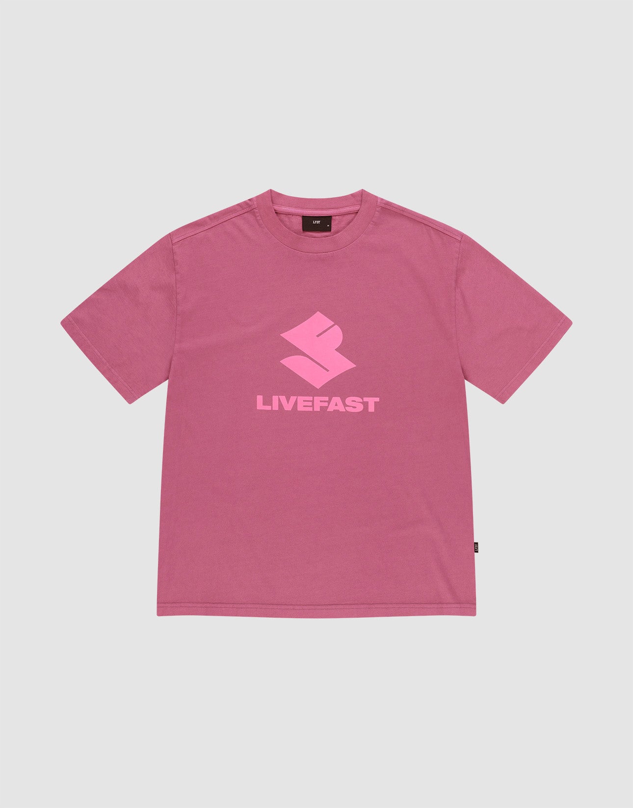 The LIVE FAST DIE YOUNG Live Fast LF Tee is a pink oversized short-sleeve t-shirt with a light pink geometric "LIVEFAST" logo, crafted from 100% Baumwolle, shown on a plain light gray background.