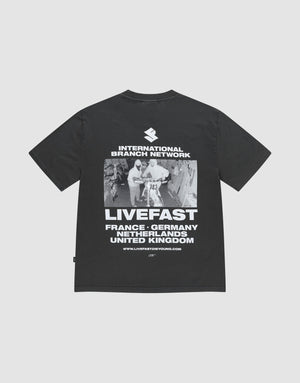 The LFDY Grand Theft Tee by LIVE FAST DIE YOUNG is an oversized black T-shirt made from 100% cotton, featuring bold front and back prints of runners, “INTERNATIONAL BRANCH NETWORK,” “LIVEFAST,” and country names. | plain