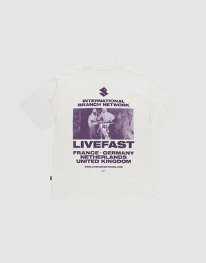 Das LFDY Grand Theft Tee von LIVE FAST DIE YOUNG ist ein weißes Oversize-Shirt aus 100% Baumwolle mit lila Backprint eines Skateboarders und Prints mit "INTERNATIONAL BRANCH NETWORK, LIVEFAST" sowie Ländernamen wie France und Germany. | plain
