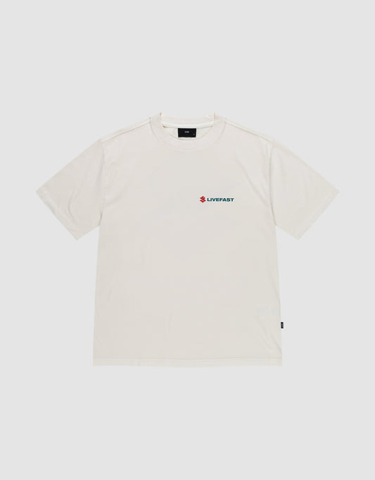 The LFDY Dealership Tee by LIVE FAST DIE YOUNG is an oversized, plain white 100% cotton short-sleeve T-shirt with a small blue and red LIVEFAST graphic on the left chest, shown against a light gray background.
