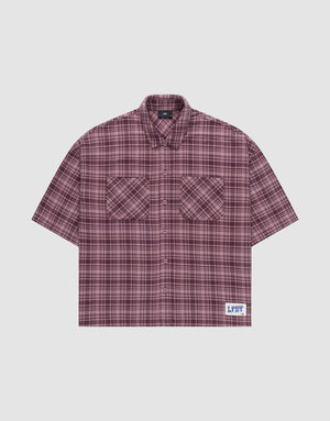 The LFDY Light Flannel by LIVE FAST DIE YOUNG is a maroon and black plaid, short-sleeve, button-up oversize fit shirt with two chest pockets and a white patch featuring blue branding near the hem. Made from 100% cotton. Laid flat on a plain background. | plain