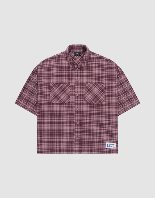 The LFDY Light Flannel by LIVE FAST DIE YOUNG is a maroon and black plaid, short-sleeve, button-up oversize fit shirt with two chest pockets and a white patch featuring blue branding near the hem. Made from 100% cotton. Laid flat on a plain background. | plain