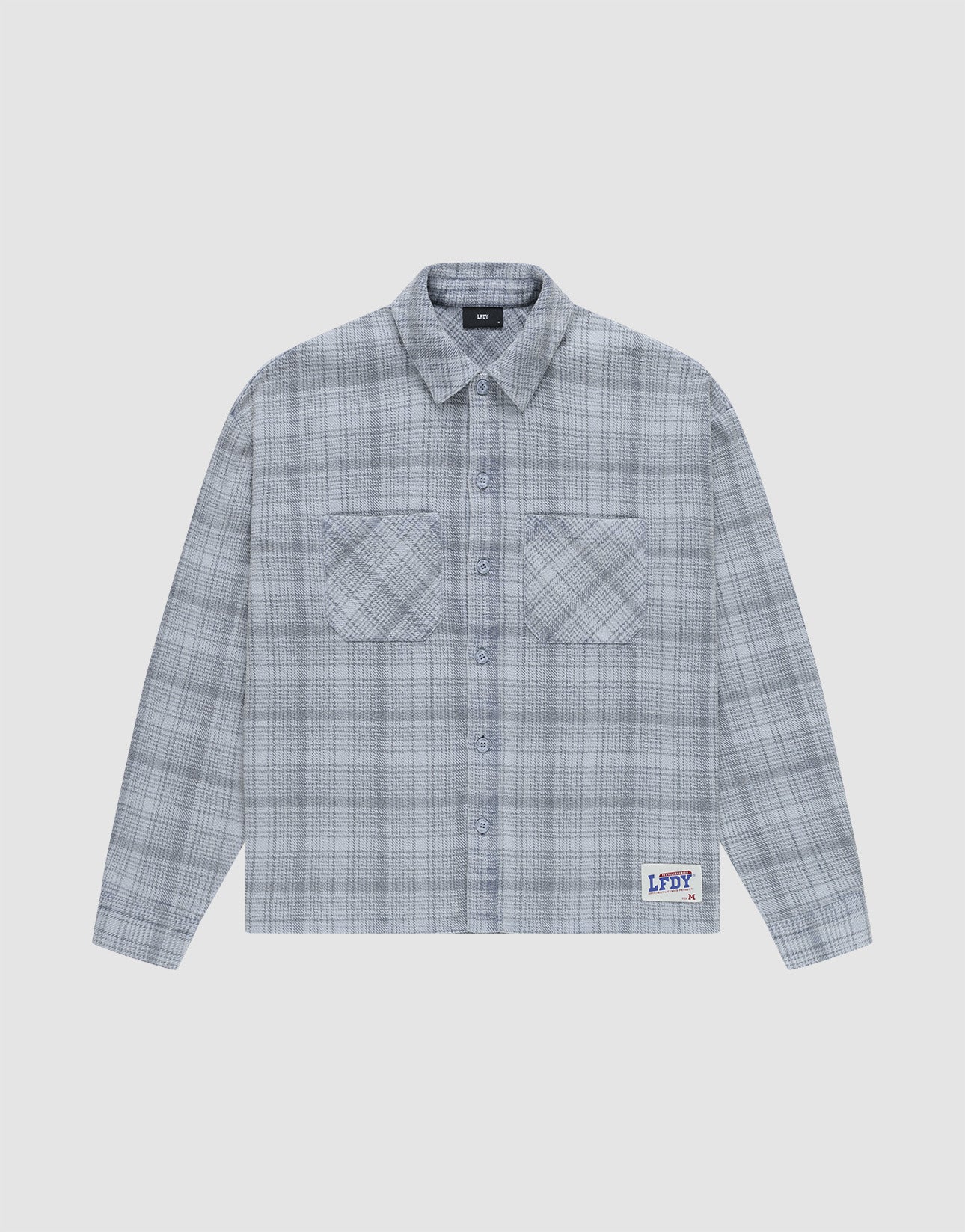 The Vintage Flannel by LIVE FAST DIE YOUNG is a gray plaid, long-sleeve, button-up shirt with two chest pockets and a small LFDY patch near the hem, featuring an oversize fit and vintage wash, shown laid flat on a white background. | plain
