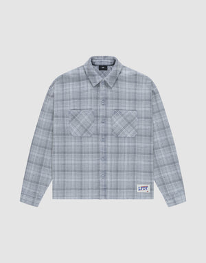 The Vintage Flannel by LIVE FAST DIE YOUNG is a gray plaid, long-sleeve, button-up shirt with two chest pockets and a small LFDY patch near the hem, featuring an oversize fit and vintage wash, shown laid flat on a white background. | plain