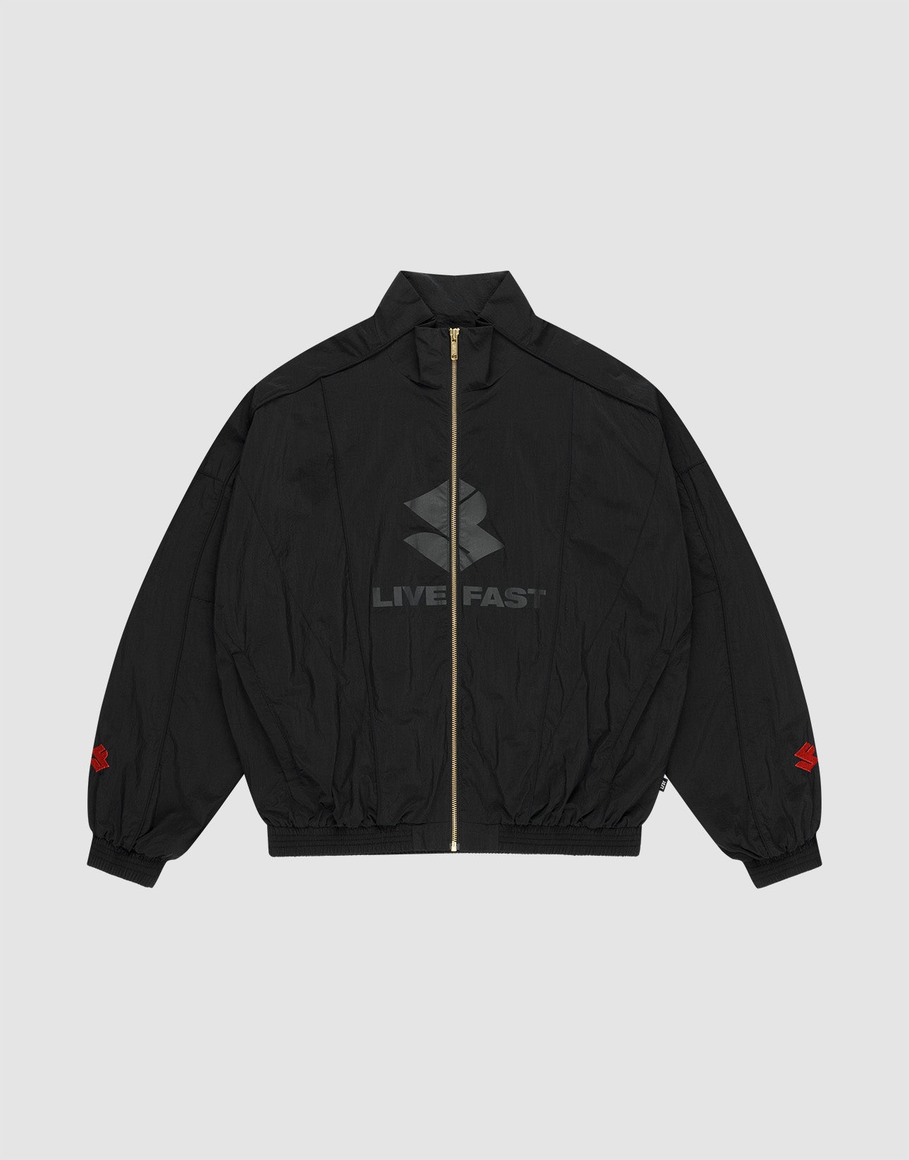 The LFDY Dealership Trackjacket by LIVE FAST DIE YOUNG is a black zip-up with Stehkragen, subtle LIVE FAST text and logo on the front, red sleeve logos near the cuffs, and a vergoldeter Reißverschluss. Background: light gray.