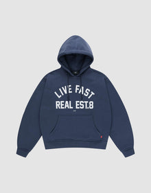 The LFDY Heavyweight Lounge Hooded by LIVE FAST DIE YOUNG is a navy blue regular-fit hoodie made from 100% Baumwolle, featuring a front pocket and "LIVE FAST REAL EST.8" in bold white letters across the chest. | plain