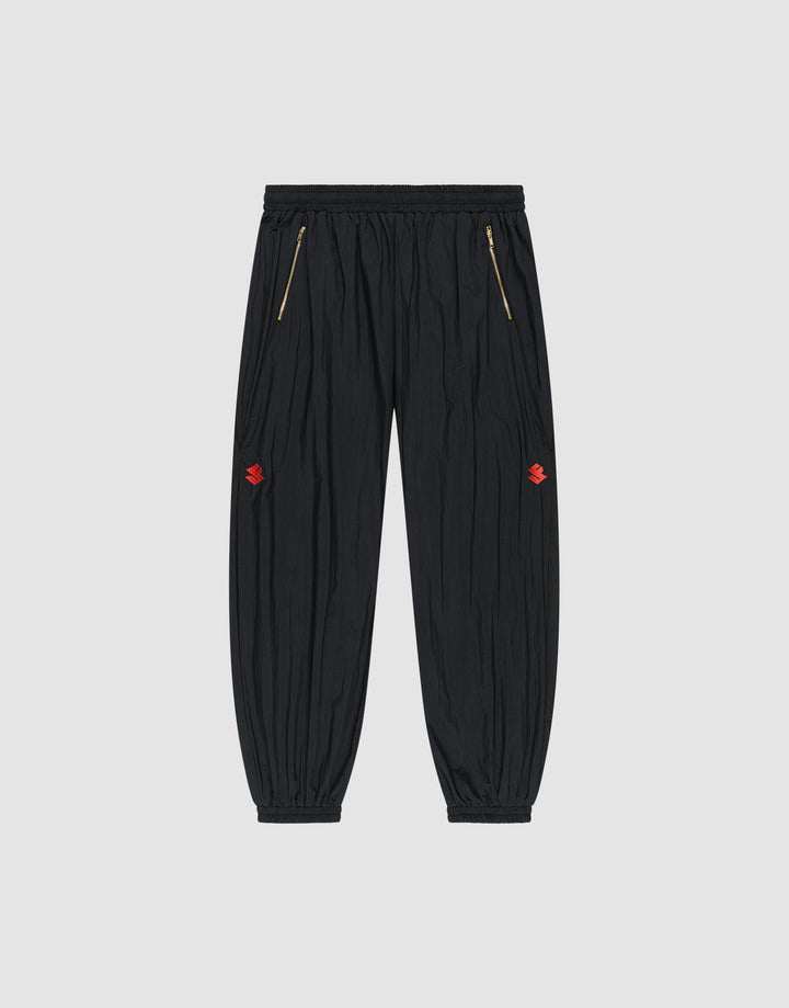 The LFDY Dealership Trackpants by LIVE FAST DIE YOUNG feature an elastic waistband, gold zippered side pockets, ankle cuffs, and small red embroidered thigh logos. Made from comfortable polyamide. Shown against a light gray background. | plain