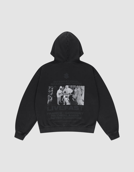 Die LFDY Grand Theft Hooded Zip von LIVE FAST DIE YOUNG ist ein Oversize-Hoodie aus Baumwolle mit Kapuze. Auf dem Rücken: Schwarz-Weiß-Foto mit zwei Personen, Graffiti und den Schriftzügen INTERNATIONAL BRAND, LIVE FAST und Ländernamen. | plain
