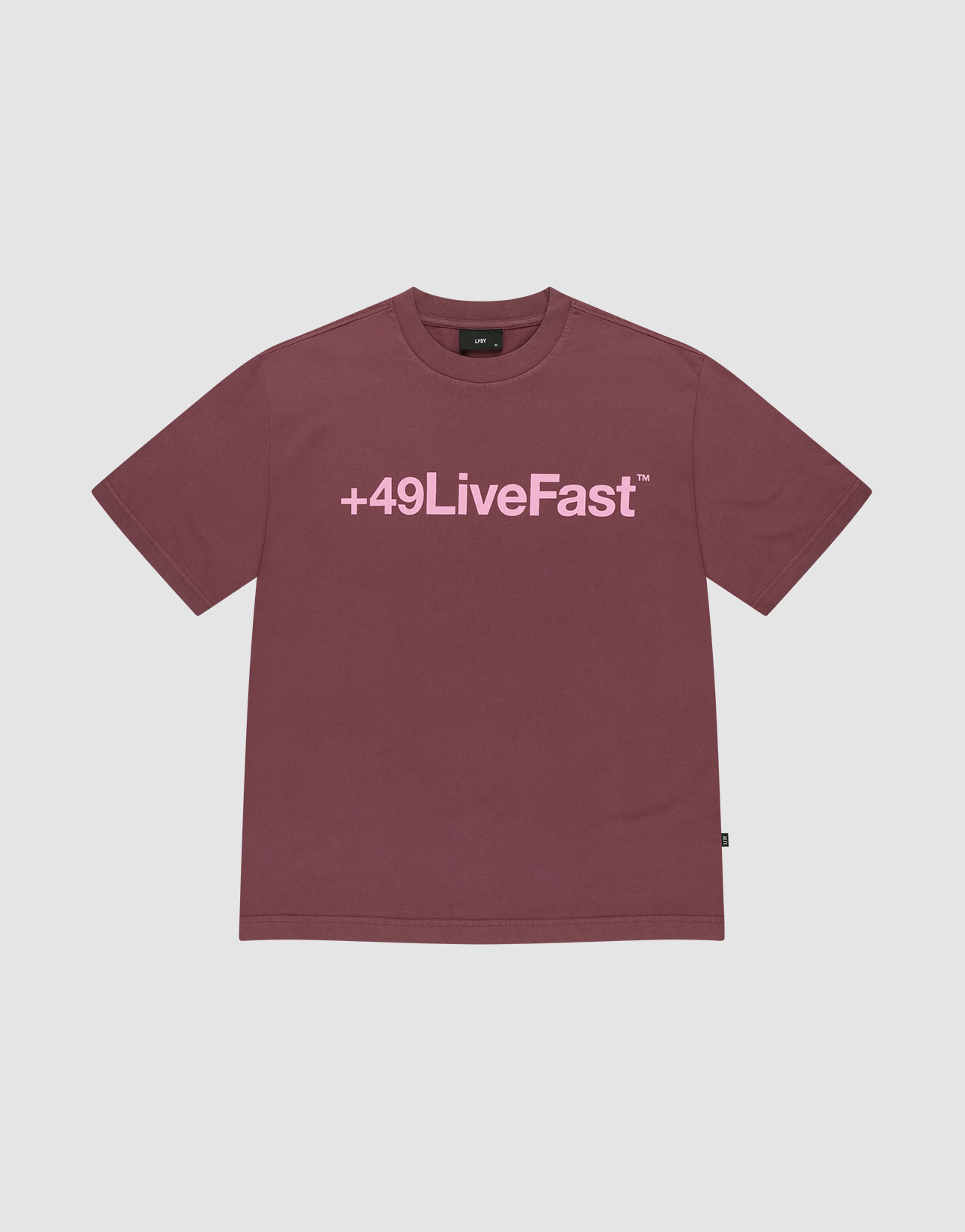The Basic +49 Tee by LIVE FAST DIE YOUNG is a maroon oversized short-sleeve shirt with a large pink +49LiveFast™ front print, made from 100% cotton and shown on a plain light gray background.