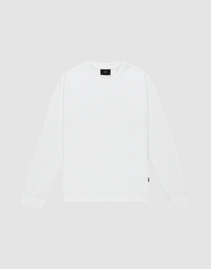 The LIVE FAST DIE YOUNG Basic Waffle Longsleeve is an oversized, plain white crew neck shirt with long sleeves, laid flat on a light gray background. It features a small black flag-label on the lower side seam and no visible patterns or logos. | plain