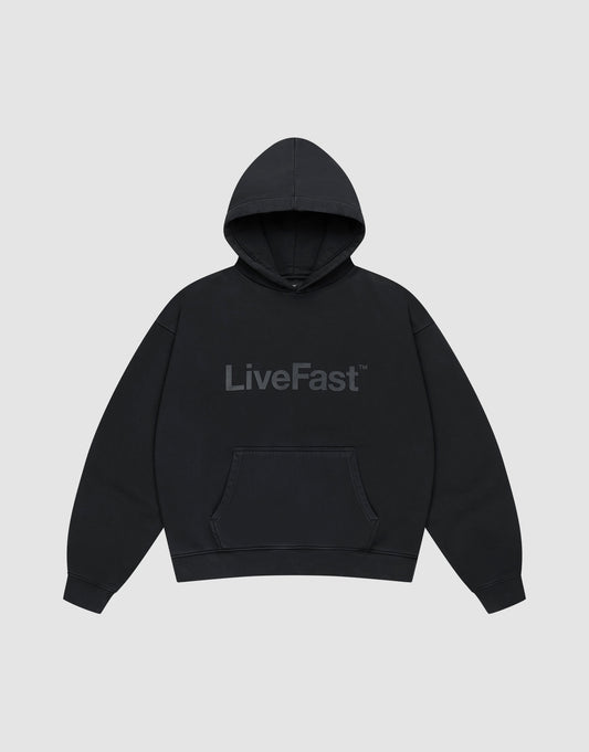 The Basic Livefast Hooded by LIVE FAST DIE YOUNG is an oversized black hoodie featuring a subtle "LiveFast" front print, crafted from soft cotton and shown against a plain light gray background. | plain