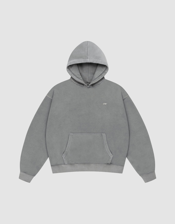 The LIVE FAST DIE YOUNG Basic Evidence Hooded is a plain gray oversized hoodie with a front pocket, hood, and small white text on the left chest. It’s styled against a plain white background.