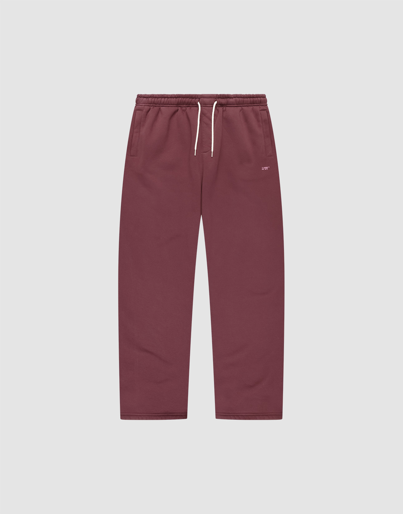 The Basic Wide Jogger by LIVE FAST DIE YOUNG features a burgundy color, elastic waistband, white drawstring, side pockets, and a small white LIVI logo-print on the left hip. The wide fit pants are shown laid flat on a light background.