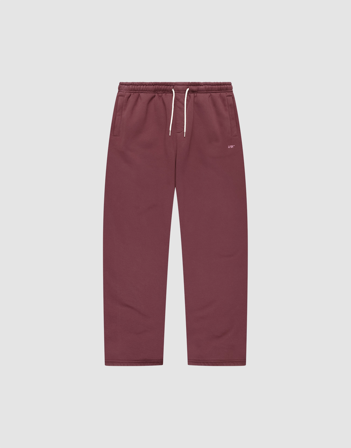 The Basic Wide Jogger by LIVE FAST DIE YOUNG features a burgundy color, elastic waistband, white drawstring, side pockets, and a small white LIVI logo-print on the left hip. The wide fit pants are shown laid flat on a light background. | plain