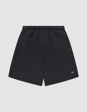 Basic Shorts by LIVE FAST DIE YOUNG in black, featuring an elastic waistband, side pockets, and a small white logo print on the lower left leg, shown against a plain light gray background. | plain