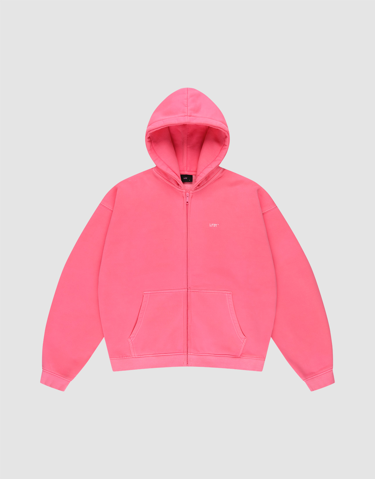 The LIVE FAST DIE YOUNG "Basic Hooded Zip" is a bright pink, oversize-fit zip-up hoodie with front pockets, a hood, and subtle white branding on the left chest, shown against a plain light gray background.
