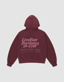 The LIVE FAST DIE YOUNG Basic 360 Hooded is a maroon oversized cotton hoodie with a hood, front and back prints including a large light purple "LiveFast Bordeaux 18-1718" text and small symbols on the back. | plain