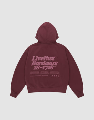 The LIVE FAST DIE YOUNG Basic 360 Hooded is a maroon oversized cotton hoodie with a hood, front and back prints including a large light purple "LiveFast Bordeaux 18-1718" text and small symbols on the back. | plain