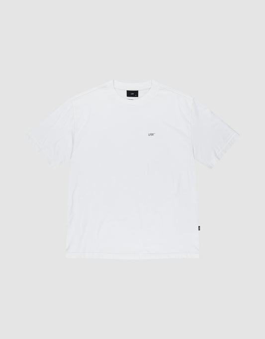 The LFDY Zizou Tee by LIVE FAST DIE YOUNG is a plain white short-sleeve crew neck T-shirt made from 100% Baumwolle. It features a small LIV* print on the left chest, a black rectangular tag at the neckline, minimal design, and a relaxed fit.