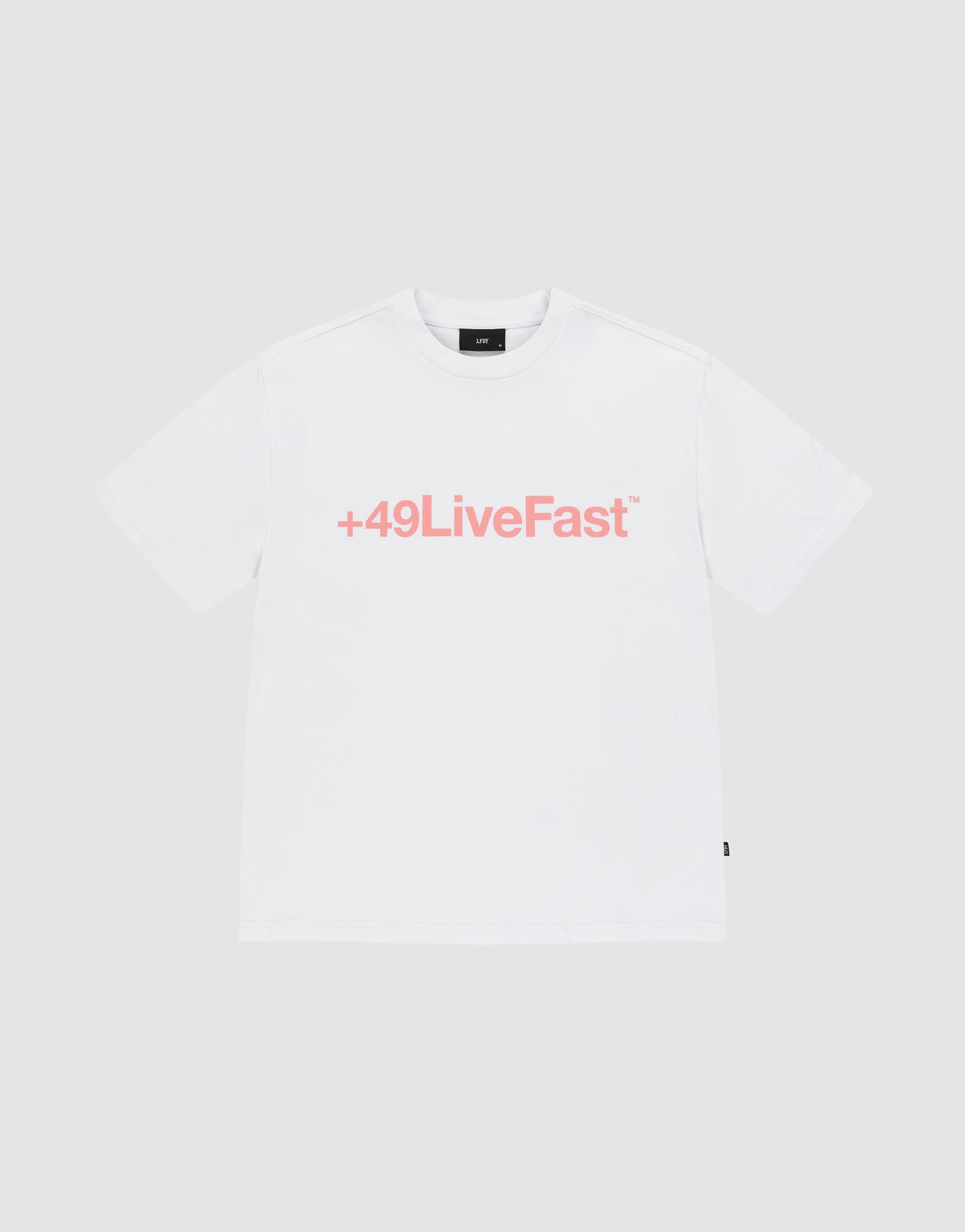 The Basic +49 Tee by LIVE FAST DIE YOUNG is an oversized white t-shirt made from 100% Baumwolle, featuring a bold pink +49LiveFast™ front print, displayed on a plain light gray background.
