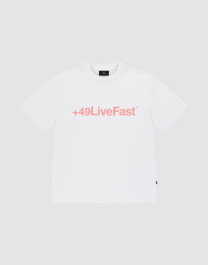 The Basic +49 Tee by LIVE FAST DIE YOUNG is an oversized white t-shirt made from 100% Baumwolle, featuring a bold pink +49LiveFast™ front print, displayed on a plain light gray background. | plain