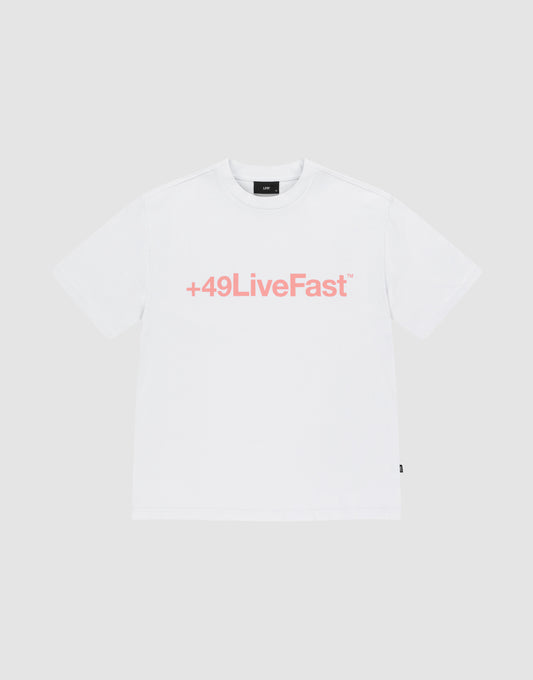 The Basic +49 Tee by LIVE FAST DIE YOUNG is an oversized white t-shirt made from 100% Baumwolle, featuring a bold pink +49LiveFast™ front print, displayed on a plain light gray background. | plain