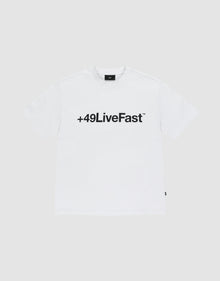 The Basic +49 Tee by LIVE FAST DIE YOUNG features a bold black “+49LiveFast™” front print on white, made from 100% Baumwolle, shown against a plain light grey background. | plain