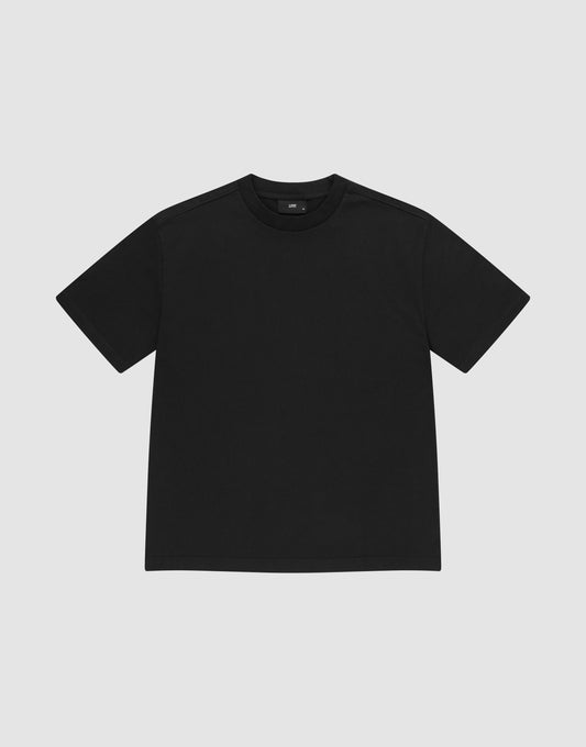 The LIVE FAST DIE YOUNG Basic Heavy Tee, a plain black short-sleeve shirt made from 100% Baumwolle, is shown laid flat on a light gray background with a classic crew neck and no visible logos or designs. | plain