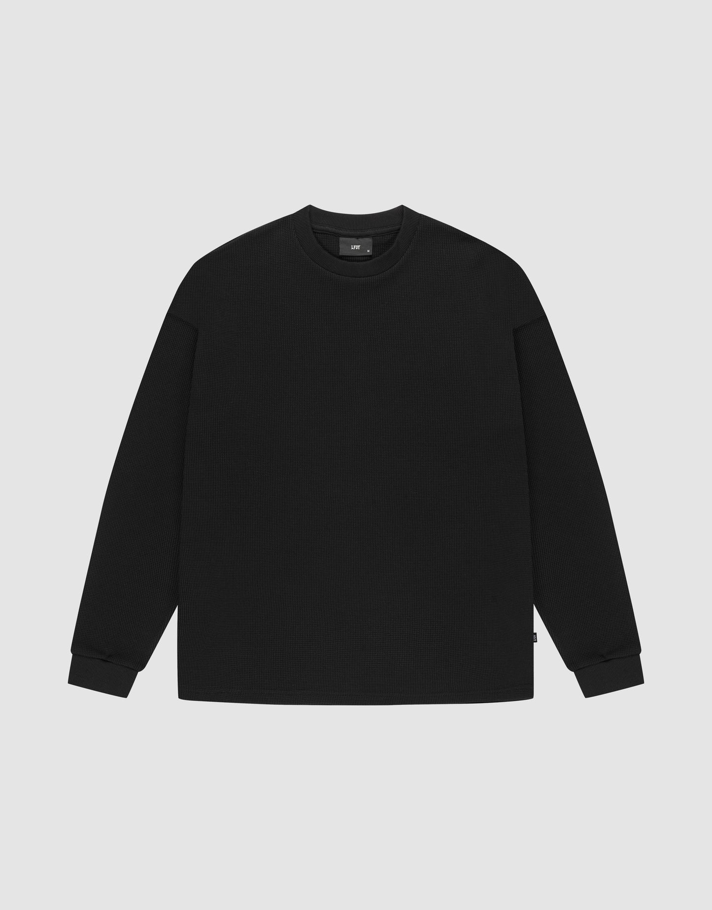 The LIVE FAST DIE YOUNG Blank Waffle Longsleeve, a black oversized crewneck sweatshirt made from 100% Baumwolle, features Ripp-Bündchen at the cuffs and neckline and is shown laid flat on a light gray background.