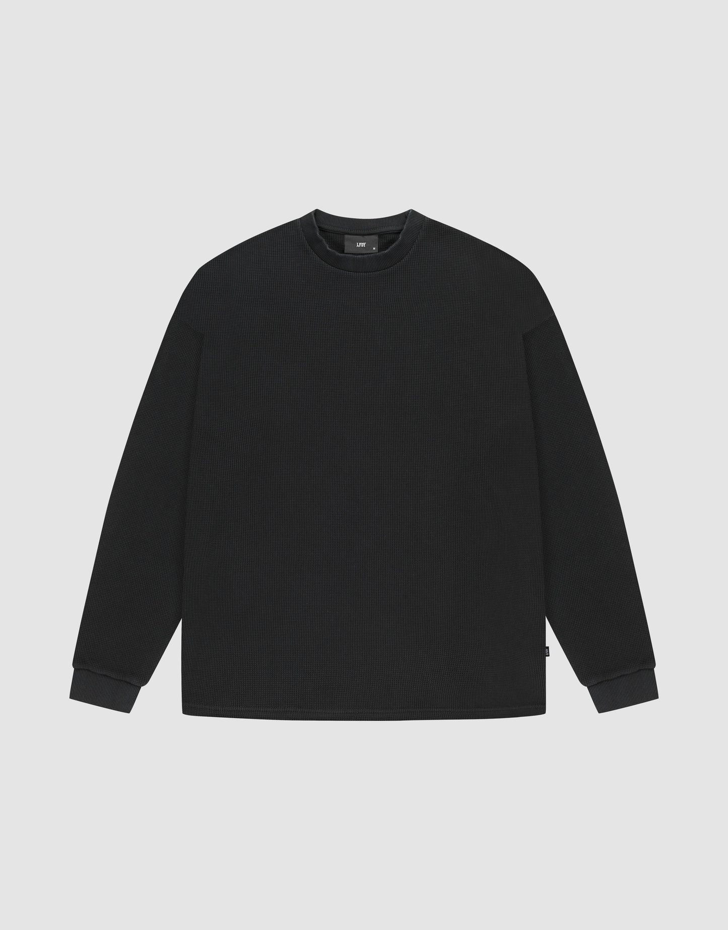 The LIVE FAST DIE YOUNG Blank Waffle Longsleeve is an oversized, plain black crewneck sweatshirt made from 100% Baumwolle, shown on a light gray background.