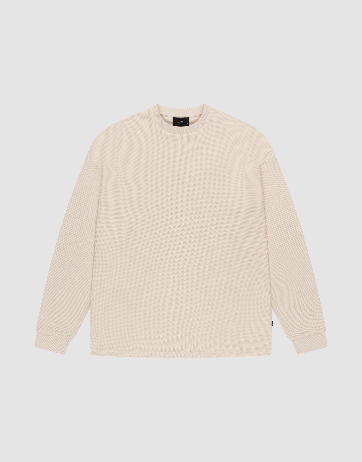 The LIVE FAST DIE YOUNG Blank Waffle Longsleeve is a beige, oversized crewneck with long sleeves and ribbed cuffs, made from 100% Baumwolle. It’s shown laid flat on a white background.