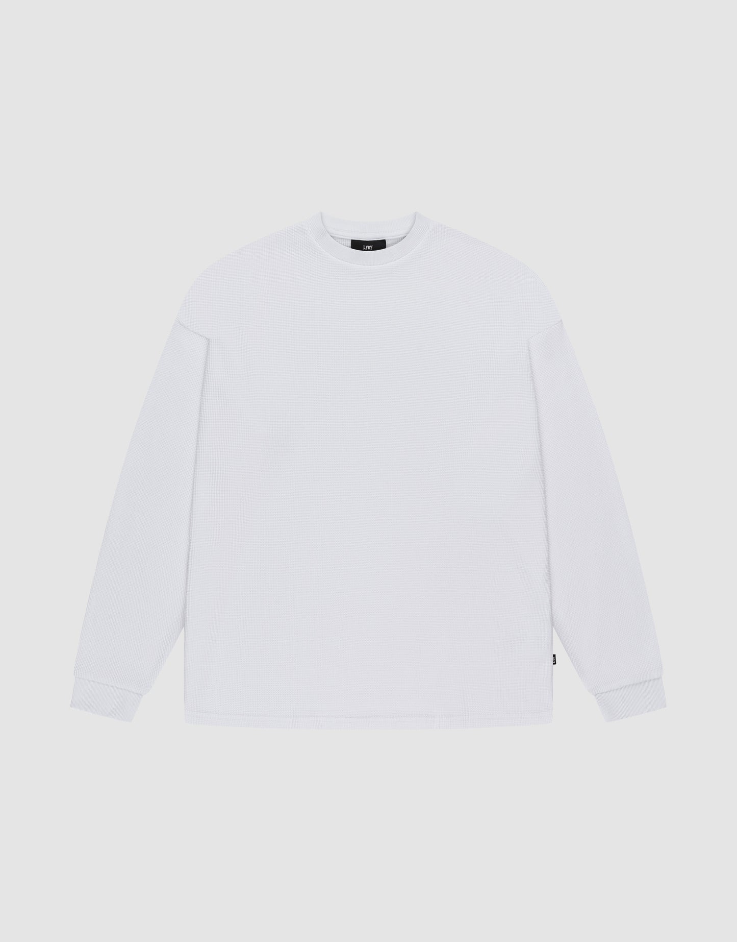 The LIVE FAST DIE YOUNG Blank Waffle Longsleeve, in Oversize Fit, is a plain white crew neck shirt with simple ribbed cuffs, made from 100% Baumwolle and featuring a minimal design without visible logos or patterns.