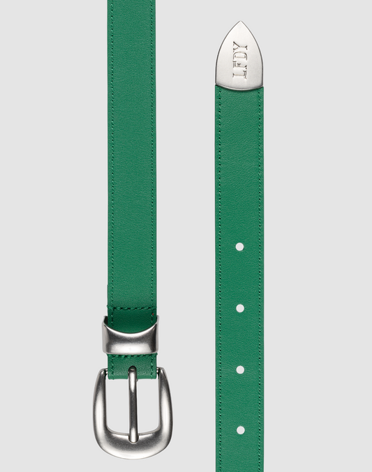 A green LFDY Slim Belt by LIVE FAST DIE YOUNG, featuring a silver buckle on the left and an engraved LOEWE logo on the pointed tip, is shown against a plain gray background. Gesamtlänge details are not visible.