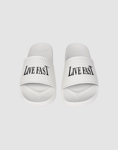 The LFDY Slides by LIVE FAST DIE YOUNG feature white PU textured straps with “LIVE FAST” in bold black letters, a comfortable EVA sole, and model number LF2606-20682.