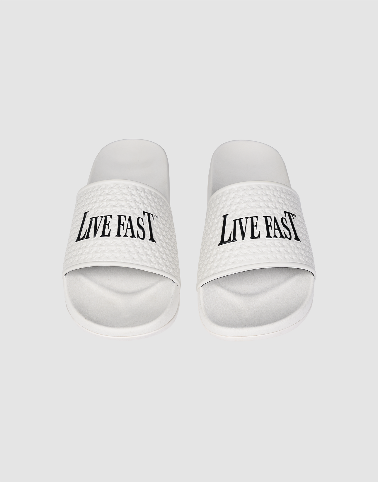 The LFDY Slides by LIVE FAST DIE YOUNG feature white PU textured straps with “LIVE FAST” in bold black letters, a comfortable EVA sole, and model number LF2606-20682.
