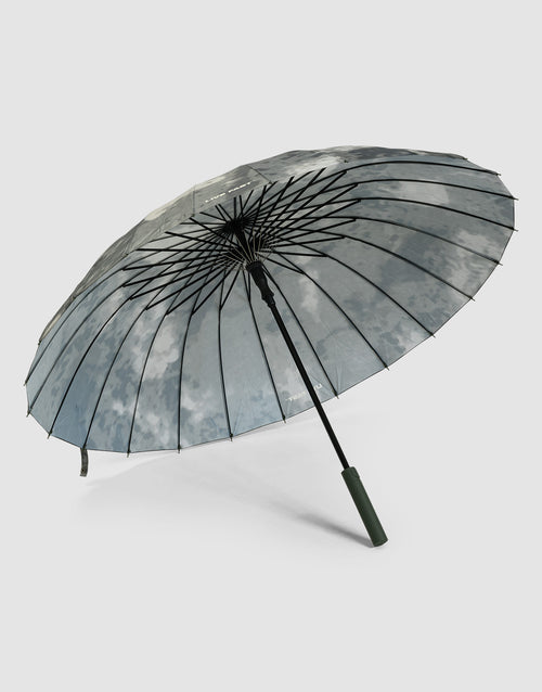 The LFDY Umbrella by LIVE FAST DIE YOUNG features a large transparent canopy with a cloudy sky print, showcased open on its side against a light gray background. It includes a stabile Rahmenkonstruktion and straight dark green handle for style and durability.