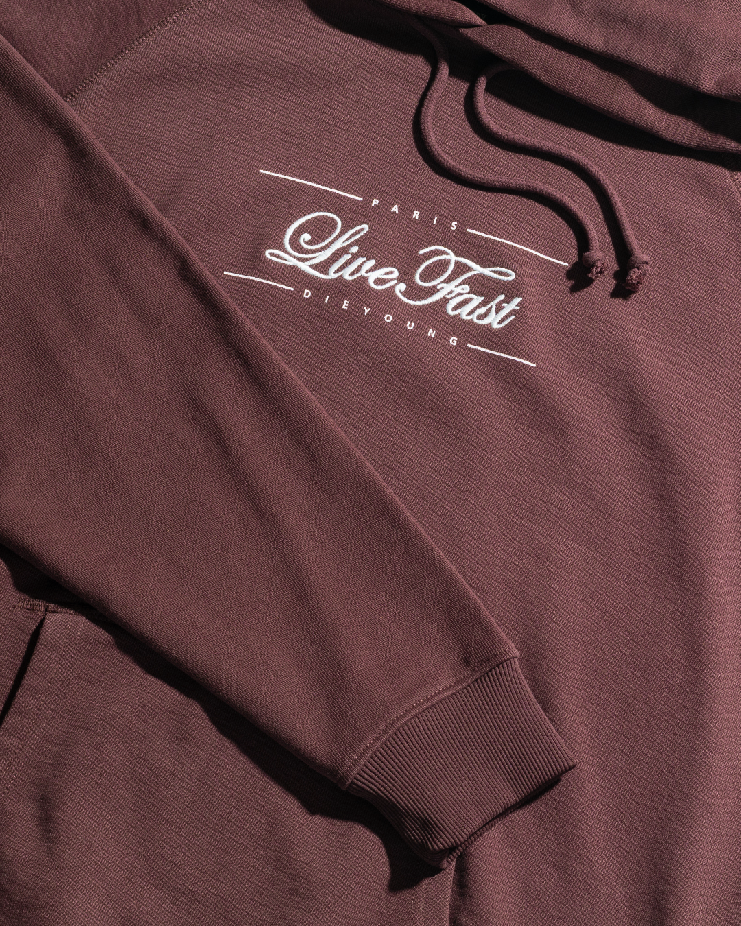 The LFDY Embroidery Hooded by LIVE FAST DIE YOUNG is a maroon Regular Fit hoodie in 100% cotton French terry, featuring PARIS Live Fast DIE YOUNG chest text, a front pocket, and drawstring hood for comfort.