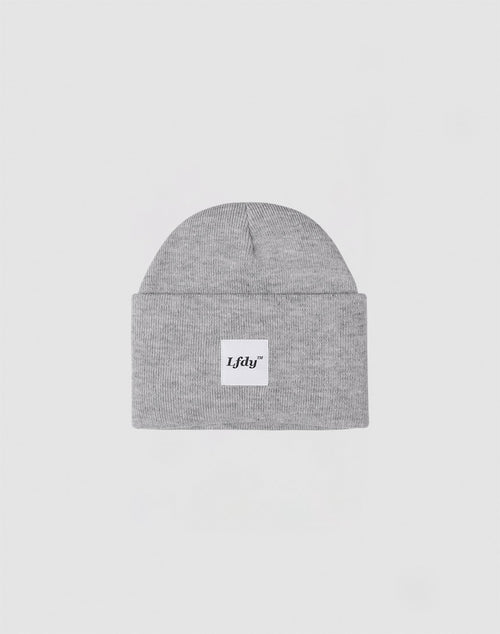 The LFDY Labeled Beanie is a light gray knit hat made from soft polyacryl, featuring a folded brim and a white patch with the bold black LFDY logo. Shown on a plain, light gray background.