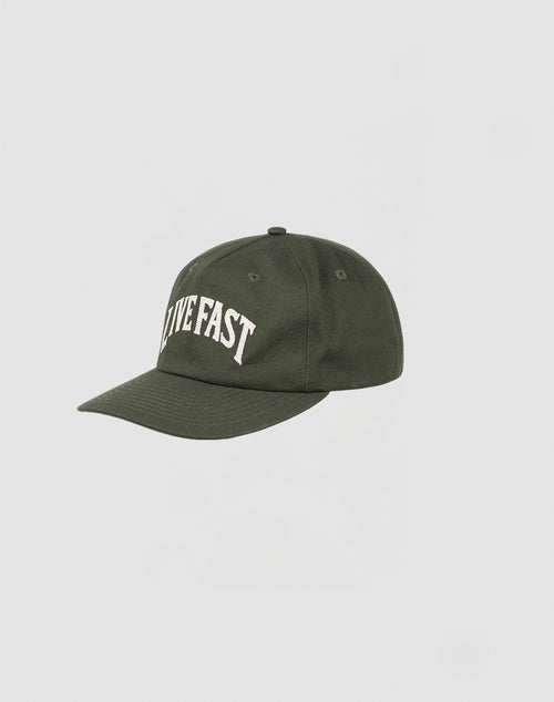 The Live Fast Unstructured Cap by LIVE FAST DIE YOUNG is a dark green 100% Baumwolle baseball cap with LIVE FAST embroidered in white and a small Flag Label, shown against a plain light gray background.