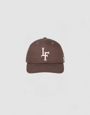 The LF Snapback by LIVE FAST DIE YOUNG is a brown baseball cap made from 100% Baumwolle, featuring a white LF logo embroidered on the front and a snap closure. It is centered against a plain light gray background.