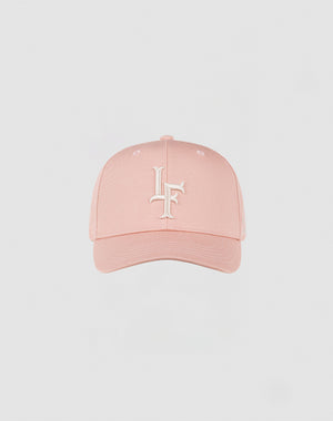 The LF Snapback by LIVE FAST DIE YOUNG is a light pink Baumwolle cap with a curved brim, white embroidered intertwined L and F on the front, and a practical snap closure, shown against a plain light background.