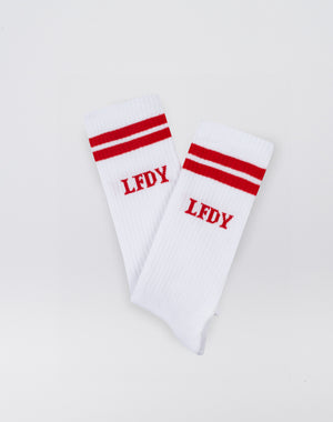 The LFDY Logo Socks (2 Pack) by LIVE FAST DIE YOUNG feature a soft Baumwolle blend with Elastan and Polyamid, two red stripes near the top, and red LFDY embroidery. Shown flat on a white background.