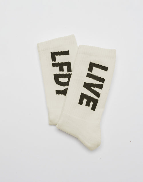 The LIVE FAST DIE YOUNG Basic Typo Socks (2 Pack) in white, One Size, feature bold black “LFDY” and “LIVE” text, made from soft Baumwolle and finished with a striking logo design. The socks are shown flat and slightly overlapping on a white background.