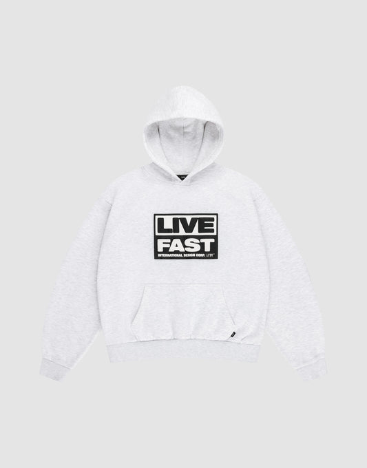 The LIVE FAST DIE YOUNG Live Fast Box Hooded sweatshirt, shown laid flat on a gray background, features an oversized fit, front pocket, and bold black and white “LIVE FAST” puffer print with smaller text beneath on the chest. | plain