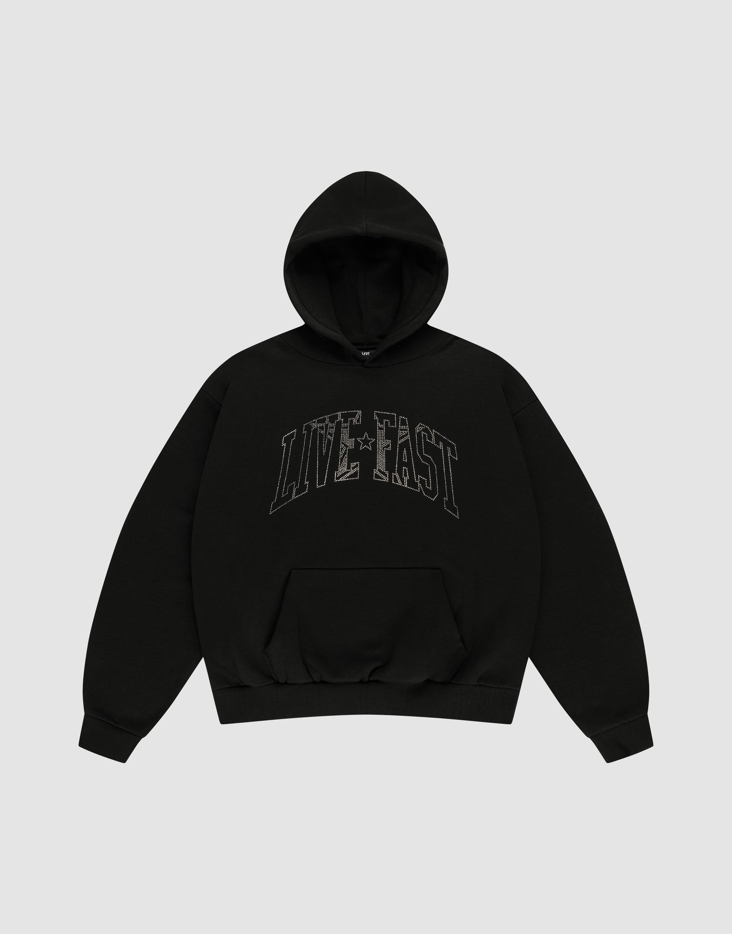 The LIVE FAST DIE YOUNG Live Fast Rhinestone Hooded is a black oversized hoodie with a double-layered hood, front pocket, and bold "LIVE FAST" outlined letters across the chest. The background is plain light gray. | plain