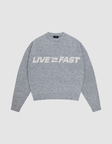The Live Fast Boucle Sweater by LIVE FAST DIE YOUNG is a gray oversized knit with "LIVE FAST" in bold white letters across the chest, shown against a plain light background. | plain