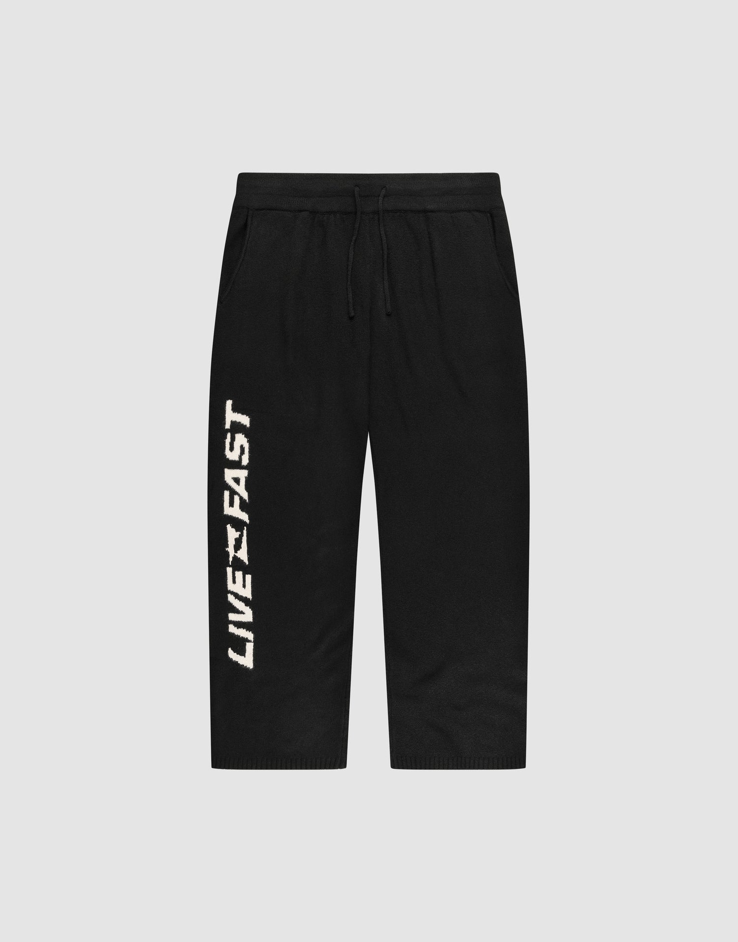 The Live Fast Boucle Pants by LIVE FAST DIE YOUNG feature an Elastik-Bund drawstring waist, a straight leg cut, and bold vertical “LIVE FAST” lettering in white on the left leg. Shown against a plain light gray background.| plain