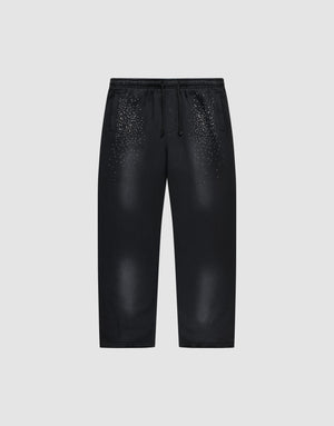 The LIVE FAST DIE YOUNG Live Fast Rhinestone Jogger is a black sweatpant with an elastic waistband and drawstrings, featuring a spray effect gradient and scattered small white dots on the upper front. Shown on a plain light gray background. | plain