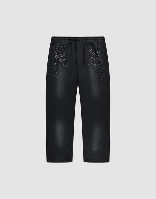 The LIVE FAST DIE YOUNG Live Fast Rhinestone Jogger is a black sweatpant with an elastic waistband and drawstrings, featuring a spray effect gradient and scattered small white dots on the upper front. Shown on a plain light gray background. | plain